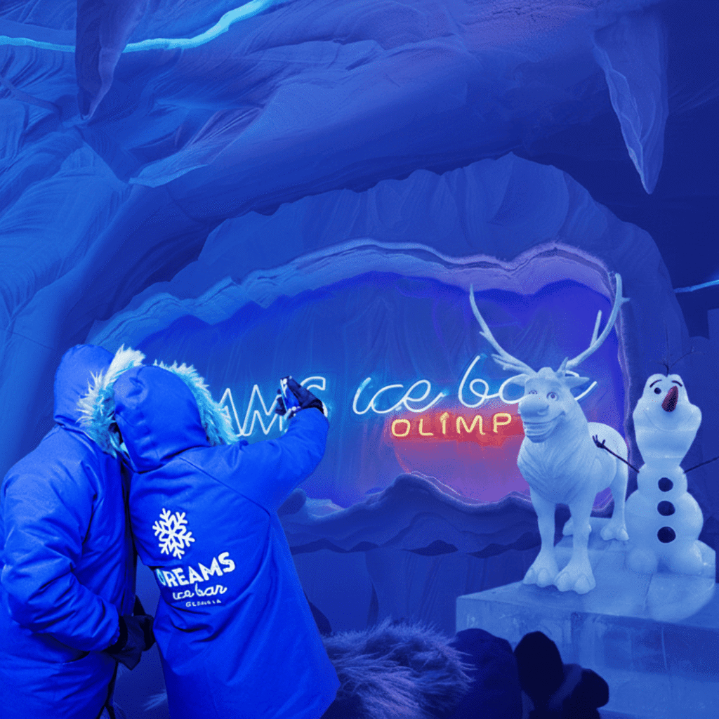 Visitantes com casacos térmicos tirando fotos no Ice Bar Olímpia, bar temático de gelo com esculturas congeladas e iluminação azul neon.
